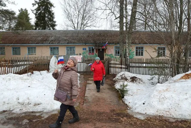 Women carry Russian flags as they leave a polling station during the presidential election in the village of Pasha in the Leningrad Region, Russia on March 16, 2024. (Photo by Anton Vaganov/Reuters)