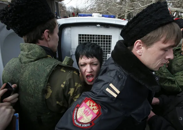 Members of Crimean self-defence units block a topless activist from the Ukrainian feminist group Femen, who is taking part in an anti-war protest near the Crimean parliament building in Simferopol, March 6, 2014. (Photo by David Mdzinarishvili/Reuters)