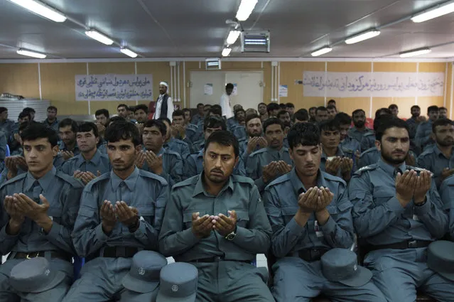 Newly graduated Afghan national police officers pray during a graduation ceremony at a National Police training center in Jalalabad east of Kabul, Afghanistan, Thursday, July 19, 2012. Over 132 National policemen graduated after receiving two months of training in Jalalabad. (Photo by Rahmat Gul/AP Photo)