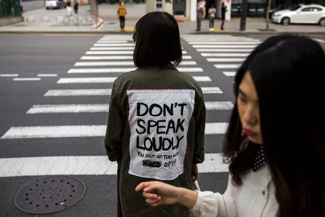 A woman wearing a jacket reading “Don't Speak Loudly” waits at a traffic light in the fashion district of Apgujeong in Seoul, May 7, 2015. (Photo by Thomas Peter/Reuters)