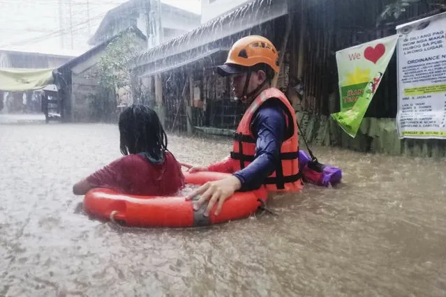 In this handout photo provided by the Philippine Coast Guard, a rescuer assists a girl as they wade through flooding caused by Typhoon Rai in Cagayan de Oro City, southern Philippines on Thursday, December 16, 2021. Tens of thousands of people were being evacuated to safety in the southern and central Philippines as Typhoon Rai approached Thursday at a time when authorities were warning the public to avoid crowds after the first infections caused by the omicron strain of the coronavirus were reported in the country, officials said. (Photo by Philippine Coast Guard via AP Photo)