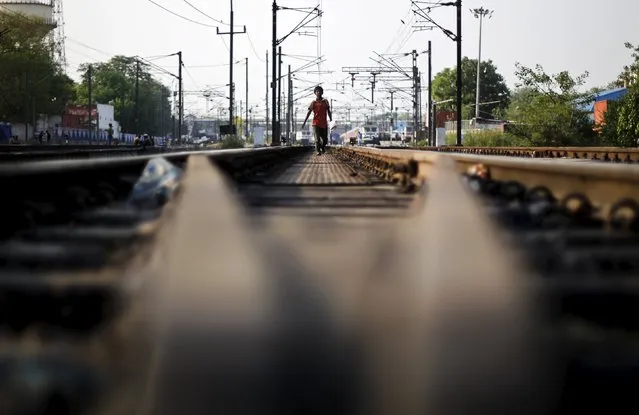A boy walks on the tracks at a railway station in New Delhi, India, May 17, 2015. (Photo by Adnan Abidi/Reuters)