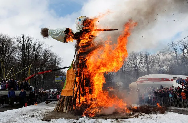 People watch a burning effigy of Lady Maslenitsa during celebrations of Maslenitsa, or Pancake Week, a pagan holiday marking the end of winter, in southern city of Stavropol, Russia, February 26, 2017. (Photo by Eduard Korniyenko/Reuters)