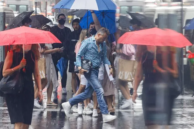 Christmas shoppers are seen in the CBD during a rain storm on December 23, 2021 in Sydney, Australia. New South Wales COVID-19 case numbers are on the increase across the state, with health authorities also reporting new cases of the Omicron variant. (Photo by Jenny Evans/Getty Images)