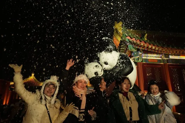 Attendees at an event that coincided with the New Year Eve cheer as fake snow from a foam machine is blown overhead in Beijing, China, Friday, December 31, 2021. (Photo by Ng Han Guan/AP Photo)