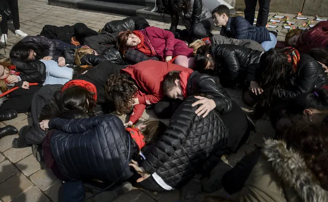 Women lay on the ground during a performance to raise awareness for the plight of women killed by their partners in Romania, marking the International Women's Day in Bucharest, Romania, Wednesday, March 8, 2017. Dozens of women lay on the ground and read out names of women, aged 16 to 66, killed by their partners in Romania in an event called “If one falls, we all fall”. (Photo by Andreea Alexandru/AP Photo)