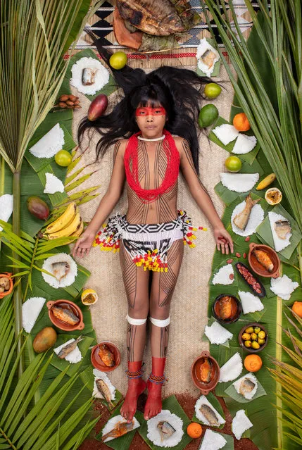 Kawakanih Yawalapiti, 9, Upper Xingu region of Mato Grosso, Brazil, 2018: Kawakanih lives with her tribe, the Yawalapiti, in Xingu national park, a preserve in the Amazon basin of Brazil. The Yawalapiti collect seeds to preserve species unique to their ecosystem, which lies between the rain forest and savannah. Kawakanih’s diet is simple, consisting mainly of fish, cassava, porridge, fruit and nuts. “It takes five minutes to catch dinner”, says Kawakanih. “When you’re hungry, you just go to the river with your net”. (Photo by Gregg Segal/The Guardian)