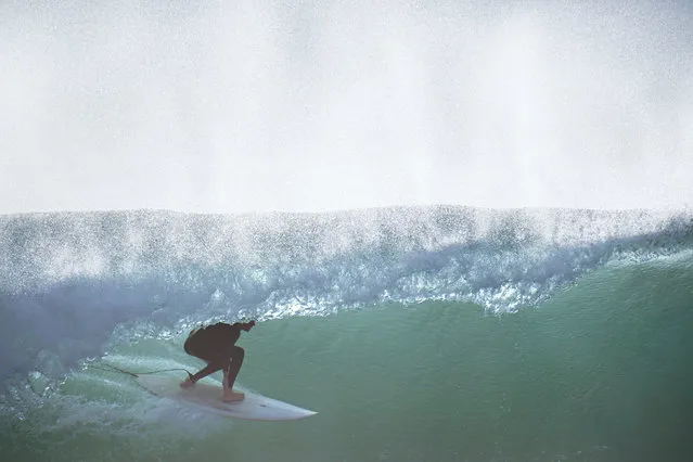 A surfer rides a wave at Blacks Beach Wednesday, January 12, 2022, in San Diego. Surfers throughout Southern California flocked to area beaches Wednesday, as a round of large surf made its way into the region. (Photo by Gregory Bull/AP Photo)