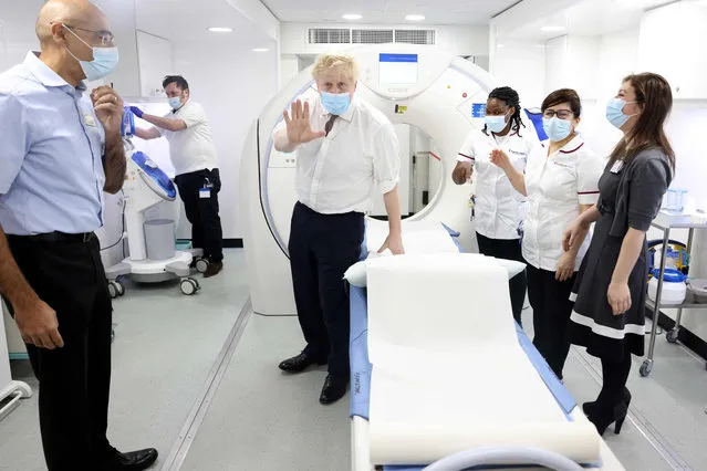 British Prime Minister Boris Johnson (C) gestures as he visits Finchley Memorial Hospital in North London on January 18, 2022. Johnson “categorically” rejected claims by his former chief aide that he lied to parliament last week about a Downing Street party held during a strict lockdown. (Photo by Ian Vogler/Pool via AFP)