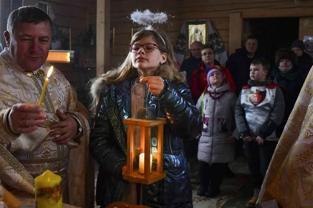 A girl holds a candle during a Christmas service at the Ukrainian Greek Catholic Church of the Holy Prophet Elijah in Kramatorsk, not far from a frontline with Russia-backed separatists in eastern Ukraine, Saturday, December 25, 2021. Pope Francis lamented ongoing conflicts in Syria, Yemen and Iraq, newly flaring tensions in Ukraine and Ethiopia, and an “unprecedented crisis” in Lebanon. (Photo by Andriy Andriyenko/AP Photo)