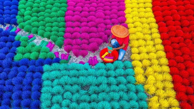 Workers in Naogaon, north Bangladesh, arrange straws made from recycled plastic to dry in the sun on November 15, 2021. They are first rinsed in salt water to clear any excess dust. (Photo by Abdul Momin/Solent News)