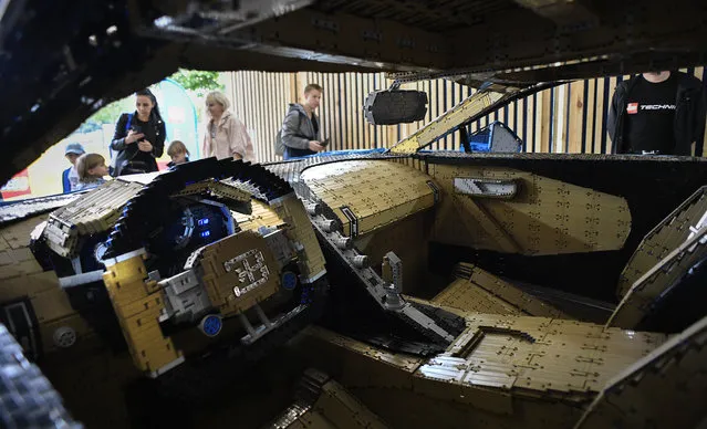 Visitors inspect a driveable full-size Bugatti Chiron car made out of LEGO Technic blocks at an exhibition in Moscow's Gorky Park on July 23, 2019. The model, which made out of over 1 million pieces and weights 1,500 kg with a top speed of 20 km/h, is on display till August 4. Lego specialists spent 13.438 hours for engineering and assembling the model without a single glue drop. (Photo by Alexander Nemenov/AFP Photo)