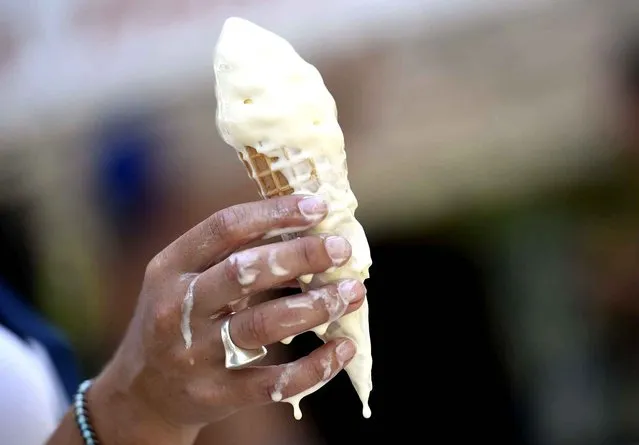 A woman eats a melting ice cream on July 2, 2015 in Paris. (Photo by Loic Venance/AFP Photo)