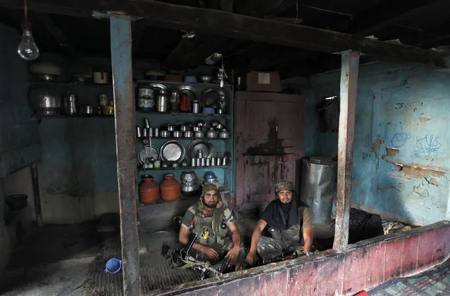 Indian army soldiers rest inside the kitchen of a residential house during search operations after a gun battle in Baban, 90 km (55 miles) north of Srinagar, July 6, 2012. (Photo by Danish Ismail/Reuters)