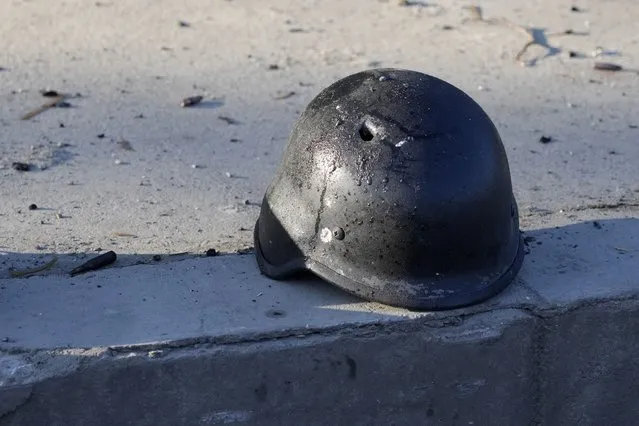 A soldier's helmet with a bullet hole near debris of burning military trucks, in a street in Kyiv, Ukraine, Saturday, February 26, 2022. Russian troops stormed toward Ukraine's capital Saturday, and street fighting broke out as city officials urged residents to take shelter. (Photo by Efrem Lukatsky/AP Photo)
