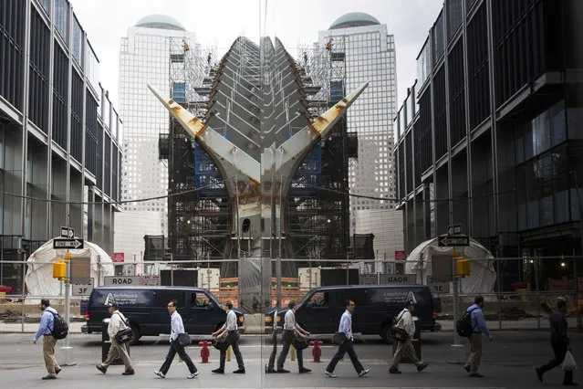 Commuters are reflected as they walk, while work continues on a new PATH terminal designed by Santiago Calatrava near Ground Zero in New York May 21, 2014. (Photo by Lucas Jackson/Reuters)
