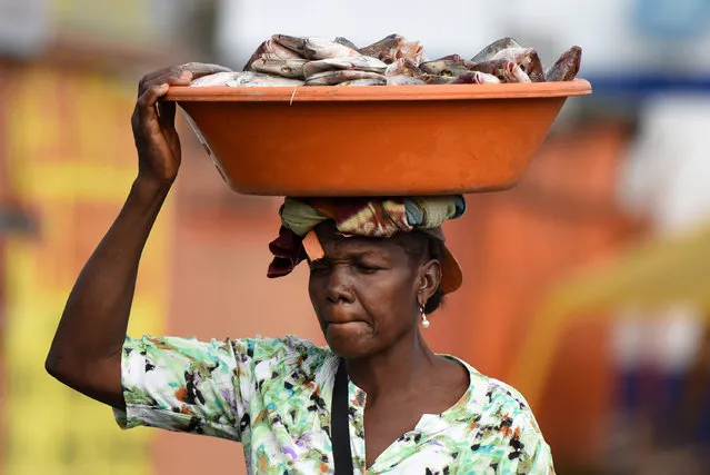 A woman sells fish at the streets in Buenaventura, Colombia's main port on the Pacific Ocean, on May 21, 2017. One policeman was dead and several injured during looting and rioting last May 19 night in Buenaventura, within a civic strike demanding improvements in health, education, roads and drinking water for this impoverished region. (Photo by Christian Escobar Mora/AFP Photo)