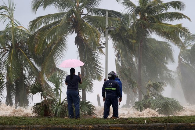 People stand in front of waves crashing against the shore as Hurricane Beryl moves south of the island, in Santo Domingo, Dominican Republic on July 2, 2024. (Photo by Erika Santelices/Reuters)