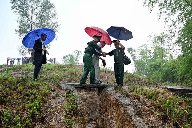 French Dien Bien Phu veteran Jean-Yves Guinard (C) walks above an old trench with the help of Vietnamese soldiers as he visits Him Lam hill (Beatrice hill) in Dien Bien Phu city on May 6, 2024. Ahead of the 70th anniversary of the Battle of Dien Bien Phu, which unfolded on May 7, 1954 and ultimately brought the French empire in Indochina to an end, three French war veterans returned to the site of the bloody conflict. (Photo by Nhac Nguyen/AFP Photo)