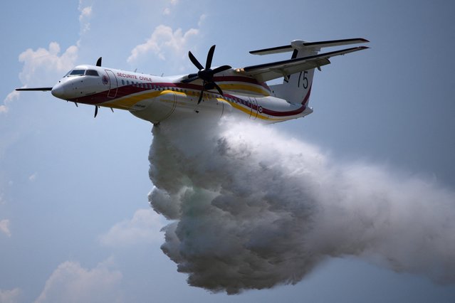 An aerial fire fighting aircraft water-bombs during an exercise as French President Emmanuel Macron visits the Nimes-Garons firefighters air base in Garons, southern France, on June 2, 2023. Macron is visiting the civil security air base to discuss prevention and fight against wildfires and to “prepare for the summer” of 2023. In 2022, 72,000 hectares, including 60,000 hectares of forest, went up in smoke in France, and 60,000 people had to be evacuated due to the fires. (Photo by Daniel Cole/Pool via AFP Photo)