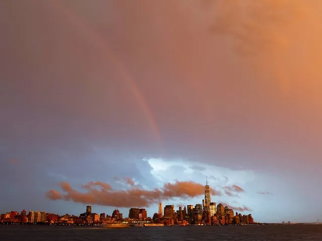 A rainbow forms over Lower Manhattan during an early evening storm in New York, July 2, 2014. (Photo by Gary Hershorn/Corbis Images)