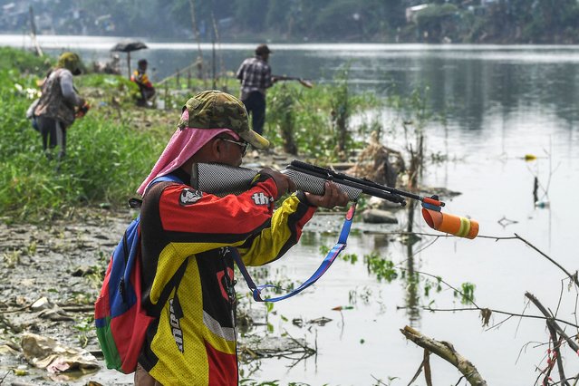 Residents using air guns try to catch fish along a floodway in Manila on October 4, 2024. (Photo by Ted Aljibe/AFP Photo)