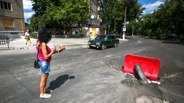 A woman photographs the remains of a shell from a multiple rocket launch system that struck a road, amid Russia's invasion of Ukraine, in Bakhmut, Ukraine June 13, 2022. (Photo by Serhii Nuzhnenko/Radio Free Europe/Radio Liberty)