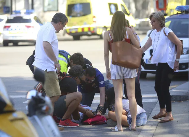 An injured person is treated in Barcelona, Spain, Thursday, August 17, 2017 after a white van jumped the sidewalk in the historic Las Ramblas district, crashing into a summer crowd of residents and tourists and injuring several people, police said. (Photo by Oriol Duran/AP Photo)