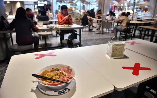 Social distancing markers are pictured on a food court table in a shopping mall amid concerns over the spread of the COVID-19 coronavirus in Bangkok on March 20, 2020. (Photo by Lillian Suwanrumpha/AFP Photo)