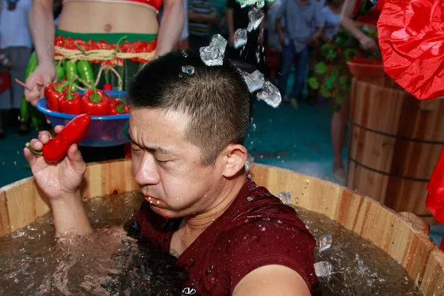 A participant eats chili as ice cubes are poured on him during a chili eating competition in Hangzhou, Zhejiang province, July 20, 2016. (Photo by Reuters/Stringer)