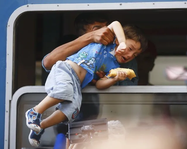 A migrant pulls a boy inside a train through a window at the Keleti train station in Budapest, Hungary, September 3, 2015. (Photo by Leonhard Foeger/Reuters)