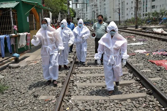 Health workers wearing protective gear walk on a railway track as they arrive in a slum area for a door-to-door verification of people to find out if they have developed any of the coronavirus disease (COVID-19) symptoms, in Kolkata, April 24, 2020. (Photo by Rupak De Chowdhuri/Reuters)