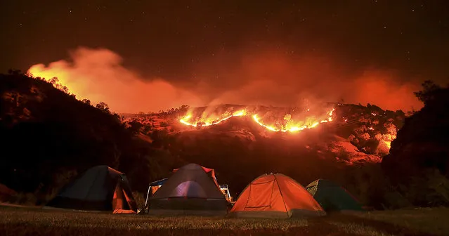 In this Tuesday, August 2, 2016 photo, as campers bed down for the night along Putah Creek, the Cold fire burns slowly downhill on the Solano and Napa County line near Lake Berryessa, Calif. (Photo by Kent Porter/The Press Democrat via AP Photo)