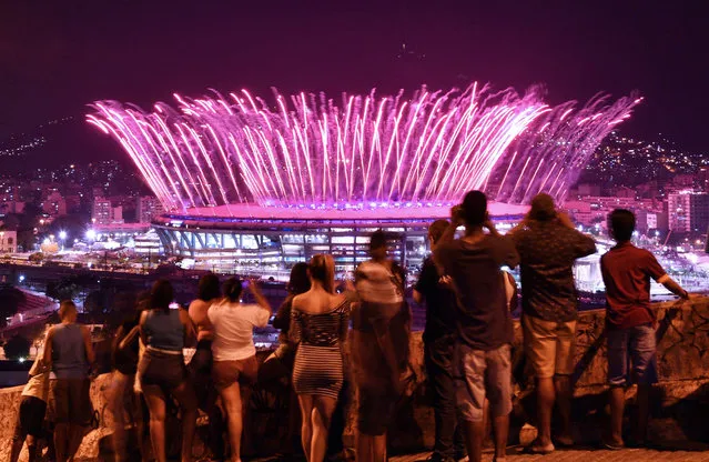 People watch fireworks exploding over the Maracana stadium, from the favela Mangueira, during the opening ceremony of the Rio 2016 Olympic Games in Rio de Janeiro on August 5, 2016. (Photo by Carl De Souza/AFP Photo)