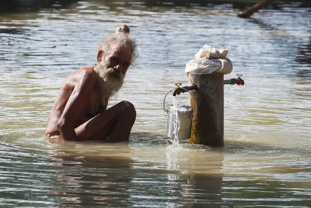 A Sadhu or a Hindu holy man baths from a tap at the flooded banks of river Ganga after heavy rains in Allahabad, India, August 9, 2016. (Photo by Jitendra Prakash/Reuters)