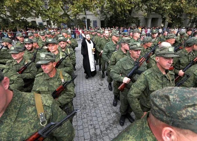 An Orthodox priest conducts a service for reservists drafted as part of the partial mobilisation, during a ceremony of their departure for military bases, in Sevastopol, Crimea on September 27, 2022. (Photo by Alexey Pavlishak/Reuters)