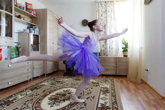 Alexandra Kustova, shows how she dances prior to an interview in her family's apartment in Yekaterinburg, a city in the Urals, Russia on Thursday, May 7, 2020. For 12-year-old Alexandra, self-isolation during the coronavirus pandemic turned out to be a blessing in disguise. Now that all the studies are conducted online, not only does she have more time for her two favorite hobbies – ballet and jigsaw puzzles – she spends more time with her family and helps out her grandmother, who lives in the same building two floors down. (Photo by Anton Basanaev/AP Photo)
