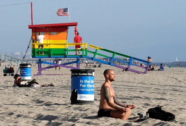 A man meditates next to the Venice Pride Lifeguard Tower after it was allowed to stay painted with the LGBTI pride flag colors in Venice, California, USA, 07 September 2017. The lifeguard tower, which had been painted rainbow colors in celebration of the 2017 LGBTI Pride Month, was due to be painted over by 08 September, but after a petition calling for the lifeguard station to be designated a permanent public art project gained over 10,000 signatures the LA County Board of Supervisors allowed it to stay painted, making it the only lifeguard station in Los Angeles county to be colored differently. (Photo by Mike Nelson/EPA/EFE)