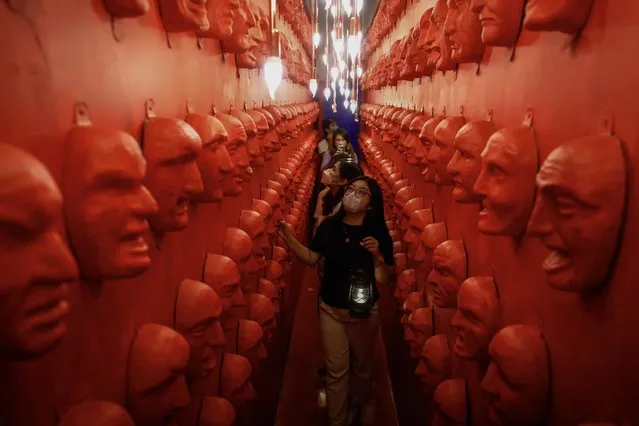 Guests go through a concept room with mask installations at Whimsical Wonderland at a commercial mall in Quezon City, Metro Manila, Philippines, 28 October 2022. The fantasy and amusement tour facility opened its doors in time for expected Halloween festivities on 31 October, featuring various creative concept rooms to spark the imagination of visitors of all ages. (Photo by Rolex Dela Pena/EPA/EFE)