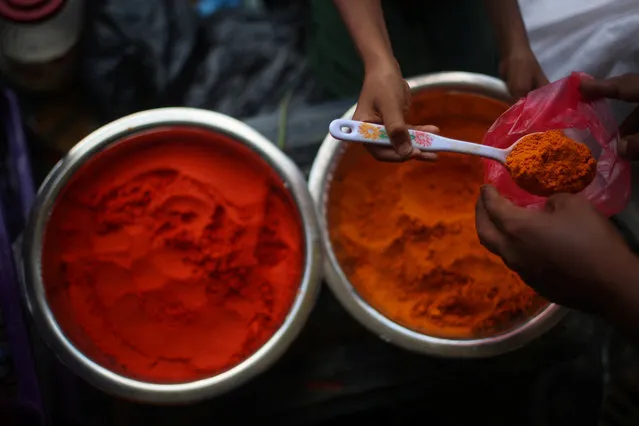 A Rohingya refugee boy, the son of Obaidul Mannan, weighs ginger powder at a stall in Palong Khali refugee camp near Cox's Bazar, Bangladesh, November 3, 2017. “The problem I'm facing here is that I'm selling next door to traders who are also selling the same items”, he said. The price for chilli and ginger powder in Palong Khali refugee camp is 30 taka per 250g. The price in Palong Khali Bazar is 27.5 taka per 250g. (Photo by Hannah McKay/Reuters)