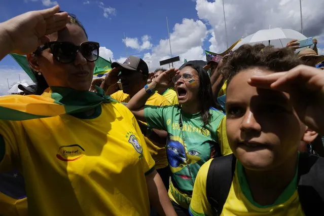Supporters of Brazilian President Jair Bolsonaro salute and sing their national anthem during a protest against Bolsonaro's run-off election loss outside the Army headquarters in Brasilia, Brazil, Tuesday, November 15, 2022. Bolsonaro supporters are calling for the Armed Forces to intervene in what they call a “fraudulent election”. (Photo by Eraldo Peres/AP Photo)