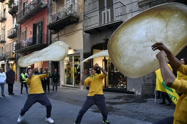 Members of the Pizzaioli Acrobats Coldiretti perform “twirling” pizza to celebrate the Unesco decision to make the art of Neapolitan “Pizzaiuolo” an “intangible heritage”, on December 7, 2017 in Naples, Italy. The art of the Neapolitan “Pizzaiuolo” is a culinary practice consisting of four different phases relating to the preparation of the dough and its baking in a wood-fired oven. The practice originates in Naples, where around 3,000 Pizzaiuoli now live and perform, and plays a key role in fostering social gatherings and intergenerational exchange. (Photo by Tiziana Fabi/AFP Photo)