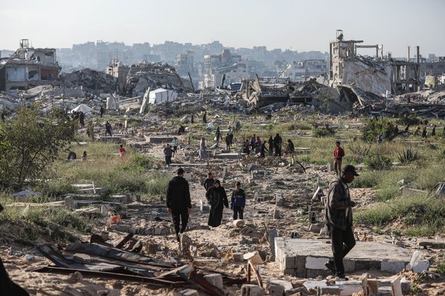 Palestinians visit the city cemetery damaged by Israeli attacks after performing the Eid al-Fitr prayer marking the end of the holy month of Ramadan in Beit Lahia, Gaza on March 30, 2025. (Photo by Abdalhkem Abu Riash/Anadolu via Getty Images)