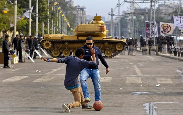 Protesters play with a ball in front of a tank securing the area around the presidential palace in Cairo, Egypt, December 14, 2012. Opposing sides in Egypt's political crisis were staging rival rallies on the final day before voting starts on a contentious draft constitution that has plunged the country into turmoil and deeply divided the nation. (Photo by Petr David Josek/Associated Press)