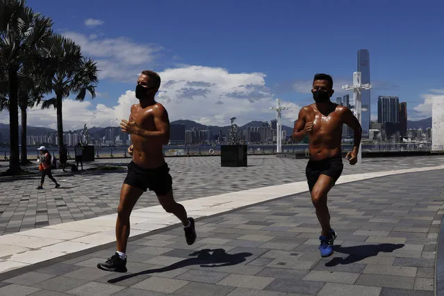 Two men wearing face masks run at a park in Hong Kong, Thursday, July 30, 2020. Hong Kong banned dining-in at restaurants completely on Wednesday and made it mandatory to wear masks in all public places, as the city battles its worst coronavirus COVID-19 outbreak to date. (Photo by Kin Cheung/AP Photo)