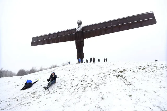 People sledge under the Angel of the North in Gateshead, England, Friday, December 29, 2017. Heavy snow, rain, thunderstorms and wind caused disruption across much of Britain as a band of “severe” weather rolled across the country. (Photo by Owen Humphreys/PA Wire via AP Photo)
