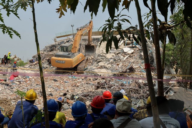Rescue workers look on as heavy construction equipment is used to look for people trapped under the rubble at the collapsed Sky Villa Condominium development in Mandalay on April 1, 2025, days after a major earthquake. Myanmar held a minute's silence on April 1 in tribute to victims of a catastrophic earthquake that has killed more than 2,000 people, buckling roads and flattening buildings as far away as Bangkok. (Photo by Sebastien Berger/AFP Photo)