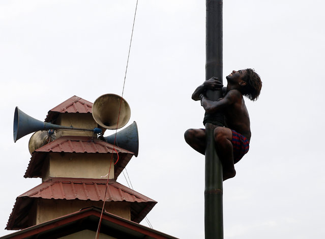 Myanmar man tries to climb to the top of slippery bamboo pole, covered with lubricating oil, as he participates in a competition on the occasion of the 70th anniversary of Myanmar's Independence Day in Yangon, Myanmar, 04 January 2018. Myanmar, also known as Burma, was colonized by Britain and became an independent republic on 04 January 1948. (Photo by Lynn Bo Bo/EPA/EFE)