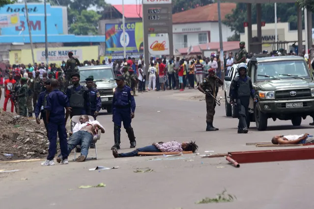 The bodies of people killed during election protests lie in the street, as Congolese troops stand near by in Kinshasa, Democratic Republic of Congo, Monday, September 19, 2016. Witnesses say at least four people are dead after opposition protests against a delayed presidential election turned violent in Congo's capital. The protests were organized by activists who are opposed to longtime President Joseph Kabila, who is now expected to stay in office after his mandate ends in December. (Photo by John Bompengo/AP Photo)