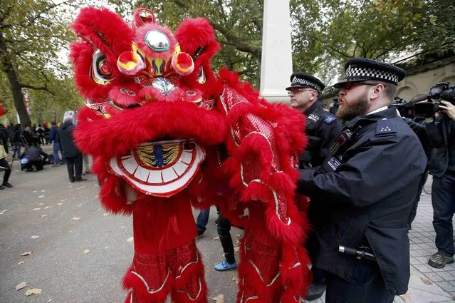 Police officers stop supporters of China's President Xi Jinping in a dragon costume from moving closer to human rights protesters waiting for China's President Xi Jinping to pass on the Mall during his ceremonial welcome, in London, Britain, October 20, 2015. (Photo by Peter Nicholls/Reuters)